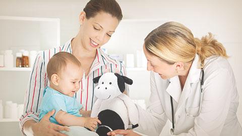 Bebé acompañado por su mamá, siendo revisado en consulta por pediatra